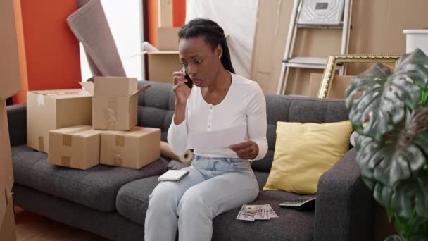 アフリカ系アメリカ人女性が新しい家で経済問題のためにスマートフォンで話す — ストック動画