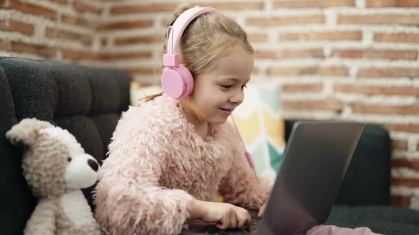 Adorable Blonde Girl Using Laptop Headphones Sitting Sofa Teddy Bear — 비디오