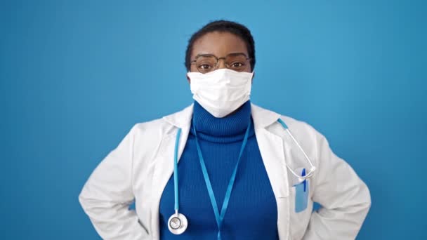 Médico Afroamericano Pie Con Máscara Médica Sobre Fondo Azul Aislado — Vídeos de Stock