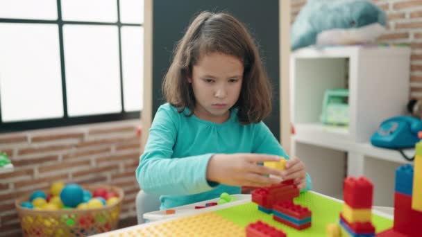 스러운 소녀가 유치원 테이블에 앉아서 자재를 가지고 — 비디오