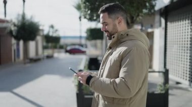 Sokakta akıllı telefon kullanan, kendine güvenen genç bir İspanyol.