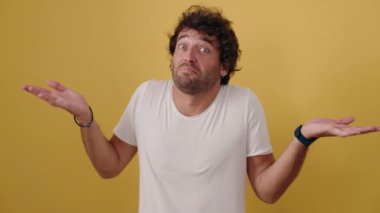 Young hispanic man standing with doubt expression over isolated yellow background