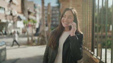 Genç İspanyol kadın gülümsüyor. Kendine güveniyor. Akıllı telefondan konuşuyor.