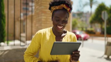Genç Afrikalı Amerikalı kadın gülümsüyor. Caddedeki touchpad 'de kendine güvenen bir şekilde video izliyor.