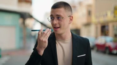 Genç İspanyol yönetici gülümseyerek caddede akıllı telefondan konuşuyor.