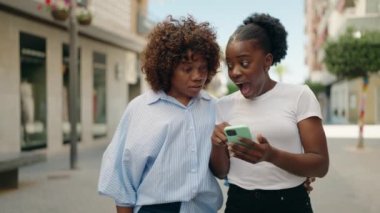 Afro-Amerikan kadın anne-kız akıllı telefon kullanıyor.