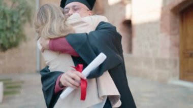 Man and woman mother and son hugging each other celebrating graduation at university