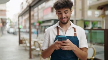 Young arab man waiter using smartphone working at restaurant