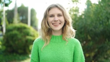 Young blonde woman smiling confident doing photo gesture with hands at park
