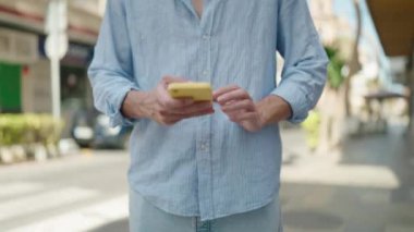 Genç İspanyol adam akıllı telefon kullanıyor. Sokakta ciddi bir ifadesi var.