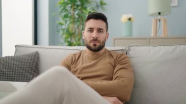 Evdeki kanepede kendinden emin gülümseyen İspanyol genç adam.