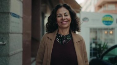 Middle age hispanic woman smiling confident walking at street