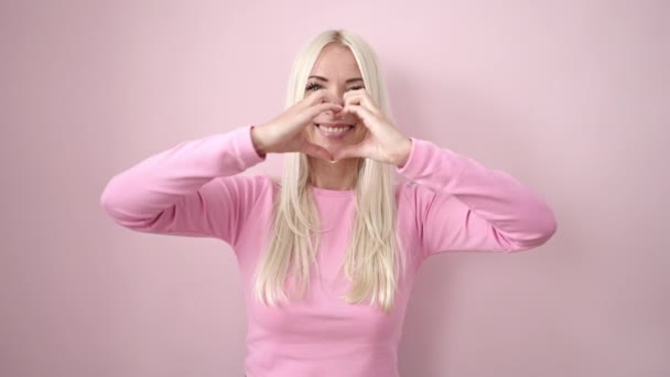 Young Blonde Woman Smiling Confident Doing Heart Gesture Hands Isolated — Stockvideo