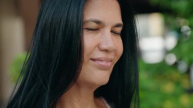 Orta yaşlı İspanyol kadın sokakta kendine güvenerek gülümsüyor.