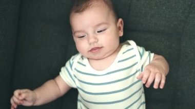 Sevimli beyaz bebek kanepede uzanmış evinde gıdıklanmaya gülümsüyor.