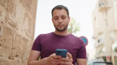 Young man using smartphone walking at street