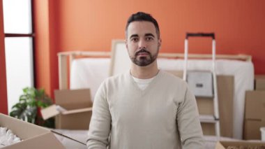 Young hispanic man smiling confident holding blackboard at new home