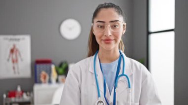 Genç, güzel İspanyol kadın doktor klinikte kendine güvenen gülümsüyor.