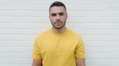 Young hispanic man smiling confident doing ok sign with thumbs up over isolated white background