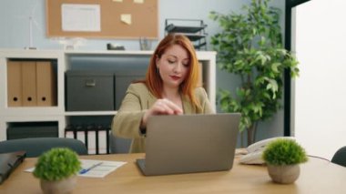 Young redhead woman business worker using laptop working at office