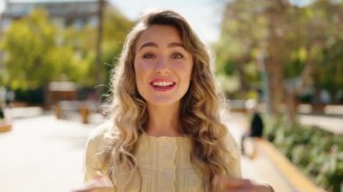 Young blonde woman smiling confident speaking at park