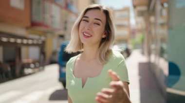 Young woman smiling confident doing coming gesture with finger at street