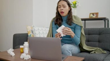 Genç ve güzel İspanyol kadın dizüstü bilgisayar kullanıyor. Kanepede oturuyor ve hasta.