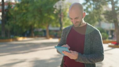 Genç kel adam parktaki dokunmatik yastığı kullanarak kendine güveniyor.