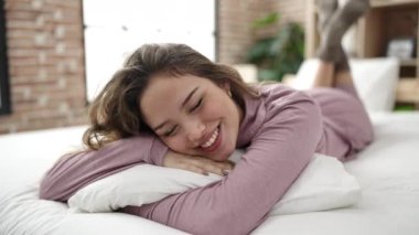 Genç ve güzel İspanyol kadın yatak odasında yastığa sarılıyor.