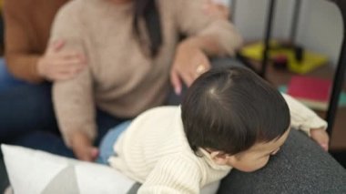 Çift ve oğul evdeki kanepede oturup birbirlerine sarılıyorlar.