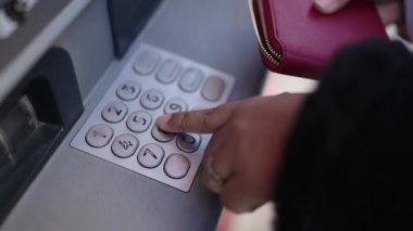 Genç Afro-Amerikalı kadın caddedeki banka ATM 'sinin şifresine basıyor.