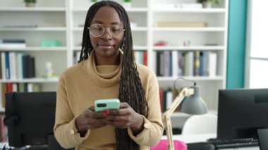 African woman smiling using smartphone at library university
