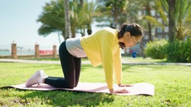 Genç Afrikalı Amerikalı kadın parkta yoga eğitimi alıyor.