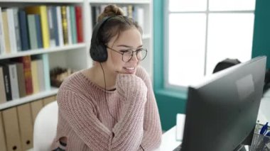 Young beautiful hispanic woman student having video call sitting on table at library university