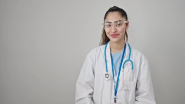Genç, güzel İspanyol kadın doktor gülümsüyor. Kendine güvenen, izole beyaz arka planda sunan.