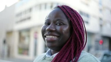 Saçları örgülü, sokakta kendine güvenen Afrikalı bir kadın.