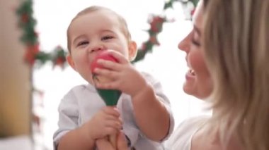 Anne ve oğlu anaokulundaki Noel süslemelerinin yanında Maraca oynuyorlar.