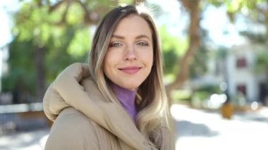 Parkta kendinden emin gülümseyen genç sarışın kadın.