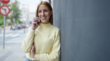Genç sarışın kadın gülümsüyor. Kendine güveni tam. Akıllı telefondan konuşuyor.