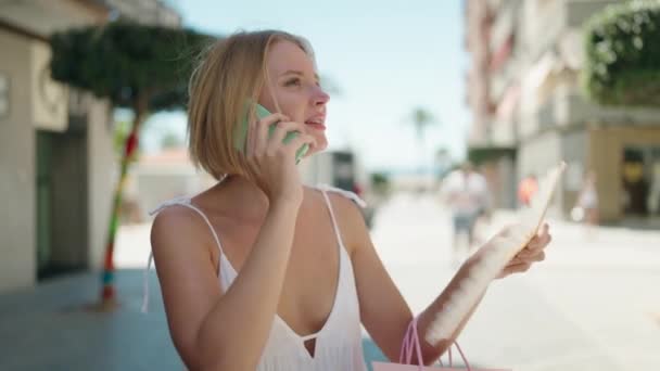 Jonge Blonde Vrouw Praten Smartphone Met Boodschappentassen Straat — Stockvideo