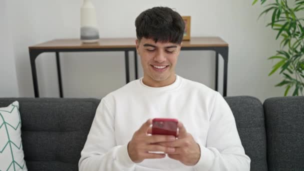 Young Hispanic Man Using Smartphone Doing Gesture Home — Vídeos de Stock