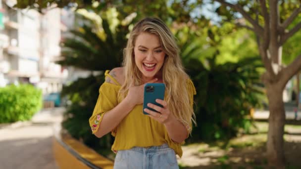 Νεαρή Γυναίκα Που Χρησιμοποιεί Smartphone Χαρούμενη Έκφραση Στο Πάρκο — Αρχείο Βίντεο