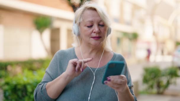 Mujer Rubia Mediana Edad Sonriendo Confiada Escuchando Música Calle — Vídeo de stock