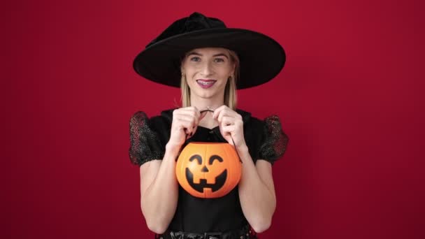 Young Blonde Woman Wearing Witch Costume Holding Pumpkin Basket Isolated — Video Stock