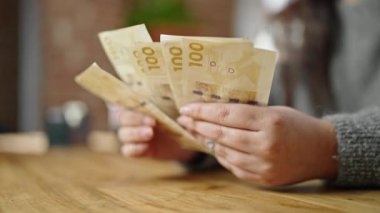 Kadının elleri odada 100 Danimarka kronu sayıyor.