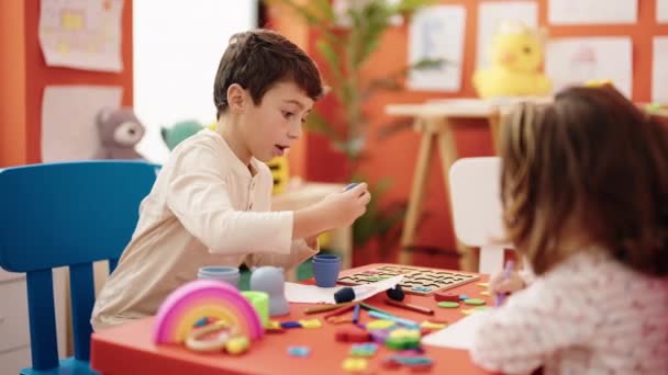 愛らしい男の子と女の子幼稚園でブロックで遊ぶ紙の上に描く就学前の学生 — ストック動画
