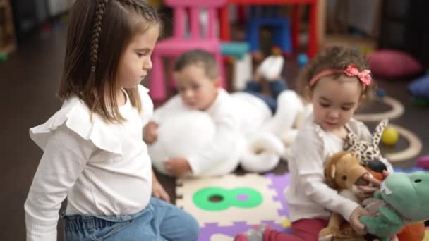 女の子と男の子のグループは 幼稚園で床に座って人形で遊んでいます — ストック動画