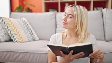 Genç ve güzel İspanyol kadın evde oturmuş kitap okuyor.