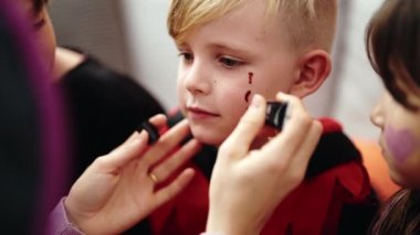 Evde cadılar bayramı makyajı yapan bir grup çocuk.