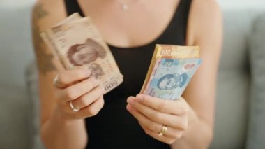 Meksika pezosu sayan genç bir kadın.